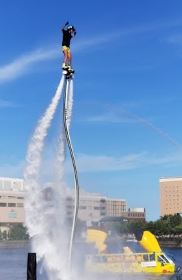 A performer on a flyboard at Pikachu Outbreak in 2018 with a pikachu boat full of pikachus in the background