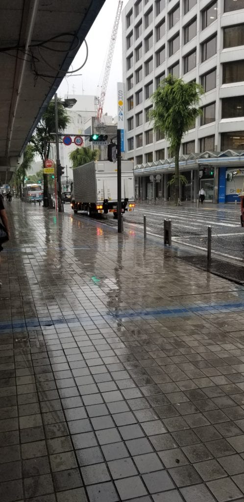 Walking Commute in Japan along street in Yokosuka with wet slippery tiles from the rain and cars driving down the street in the early morning