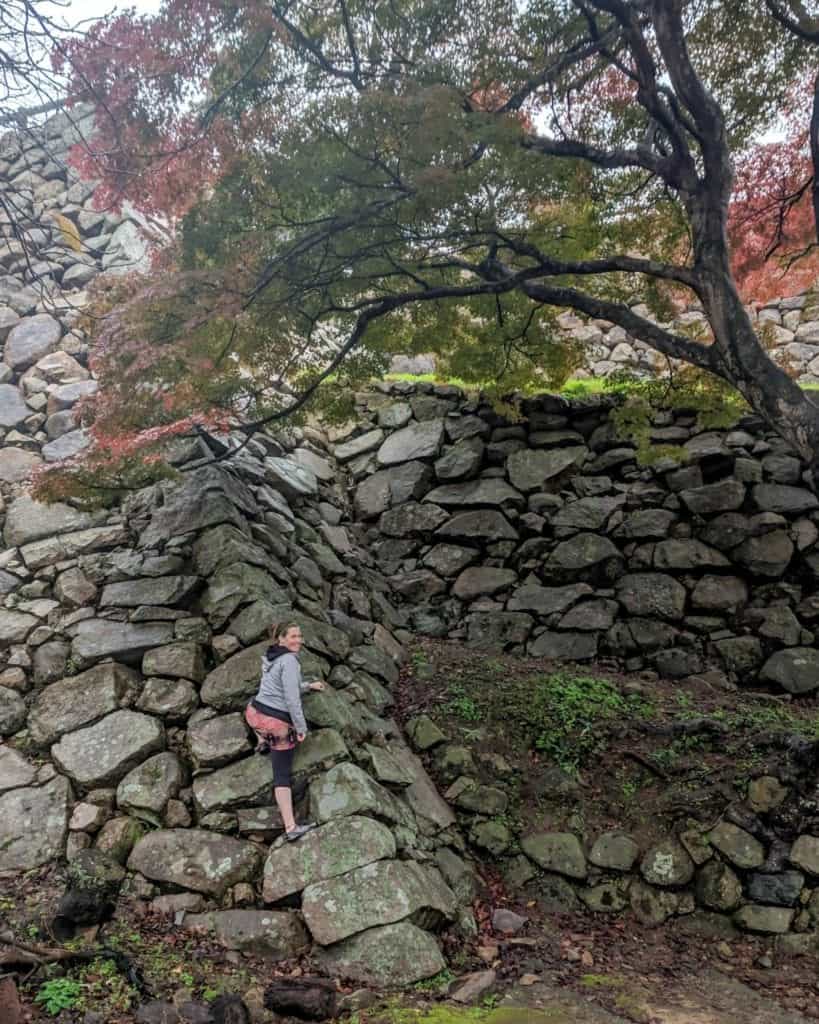 A Young Woman climbs the stones remaining on the castle walls of Tottori Castle Ruins