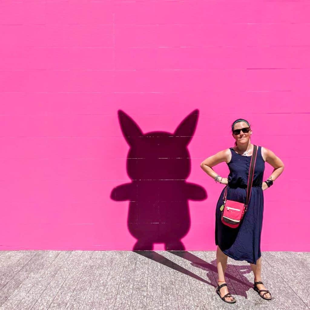 Kristen Abroad standing in front of a Pikachu shadow mural at the Pikachu Outbreak event in 2019